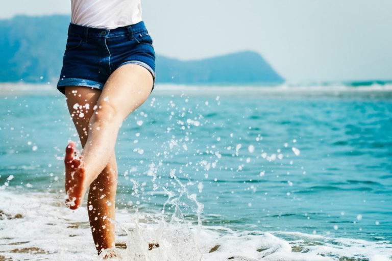 woman kicking up sand on a beach.