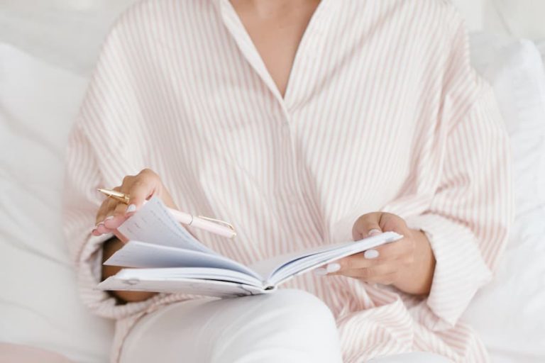 woman sitting in bed with paper planner completing an evening routine.