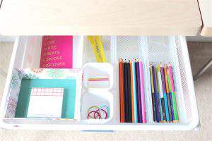 desk drawer filled with colorful office supplies organized with drawer dividers.