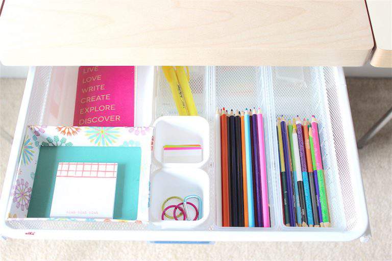desk drawer filled with colorful office supplies organized with drawer dividers.