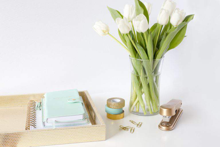 organized home office desk with bouquet of flowers.