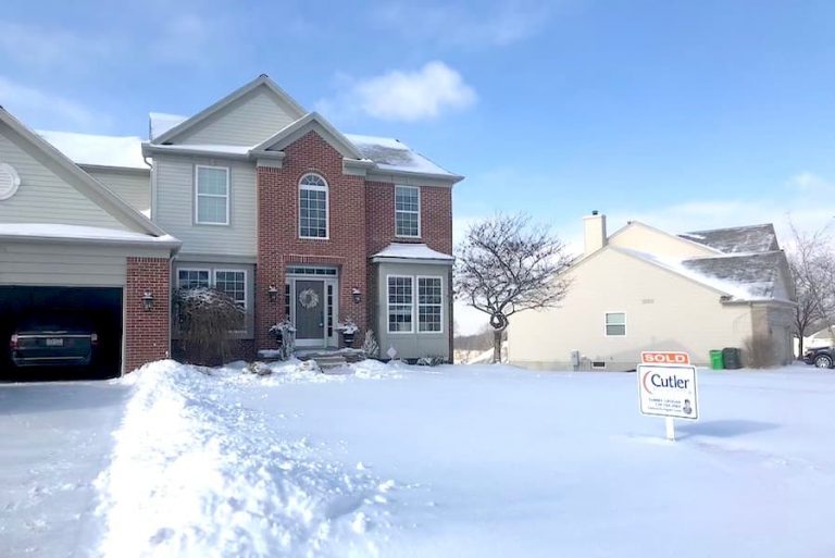 house with snow in front yard and SOLD real estate sign.