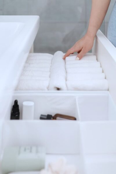 woman's hand organizing towels in a pristinely organized bathroom drawer.